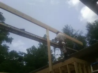 Carpenter setting a ridge beam over a new addition frame — Ice Dam Removal by Roofing Brothers in Lake Milton
