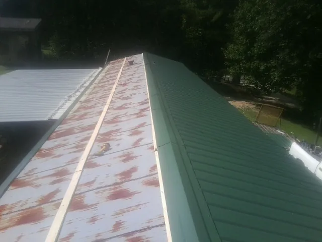 Old rusted panels beside newly installed green metal roofing — Wind Damage Roof Repair by Roofing Brothers in Lake Milton