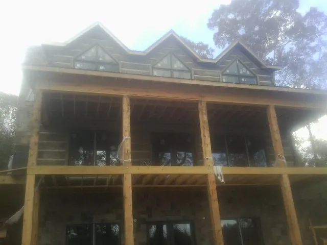 Dormers and porch framing on a large log home under construction — Roof Coating work by our crew in Lake Milton