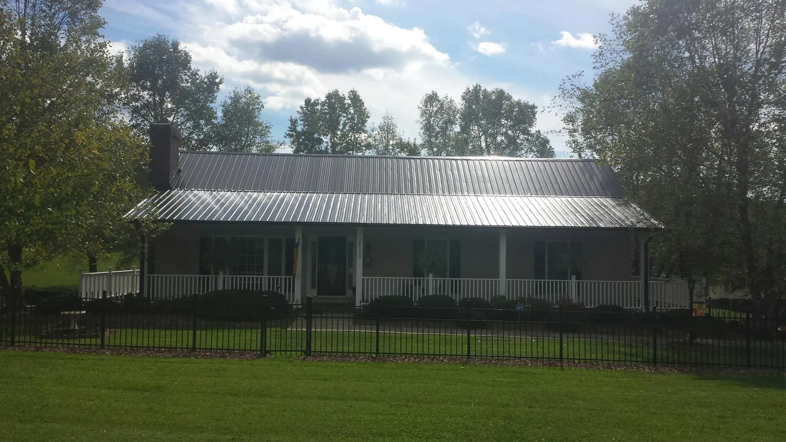 Gray metal roof on a brick ranch with a full width front porch — Gutter Guard Installation work by our crew in Lake Milton