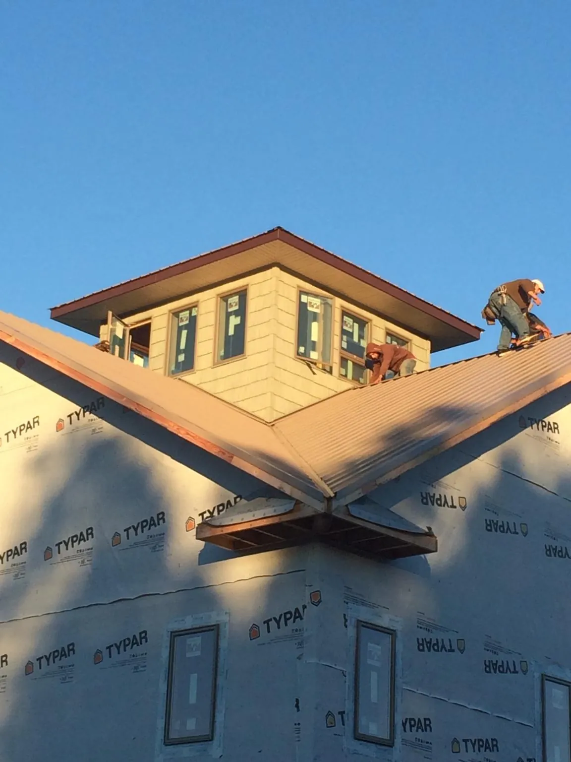Roofers working around a rooftop cupola on a new metal roof at sunset — Roof Waterproofing in Lake Milton by Roofing Brothers